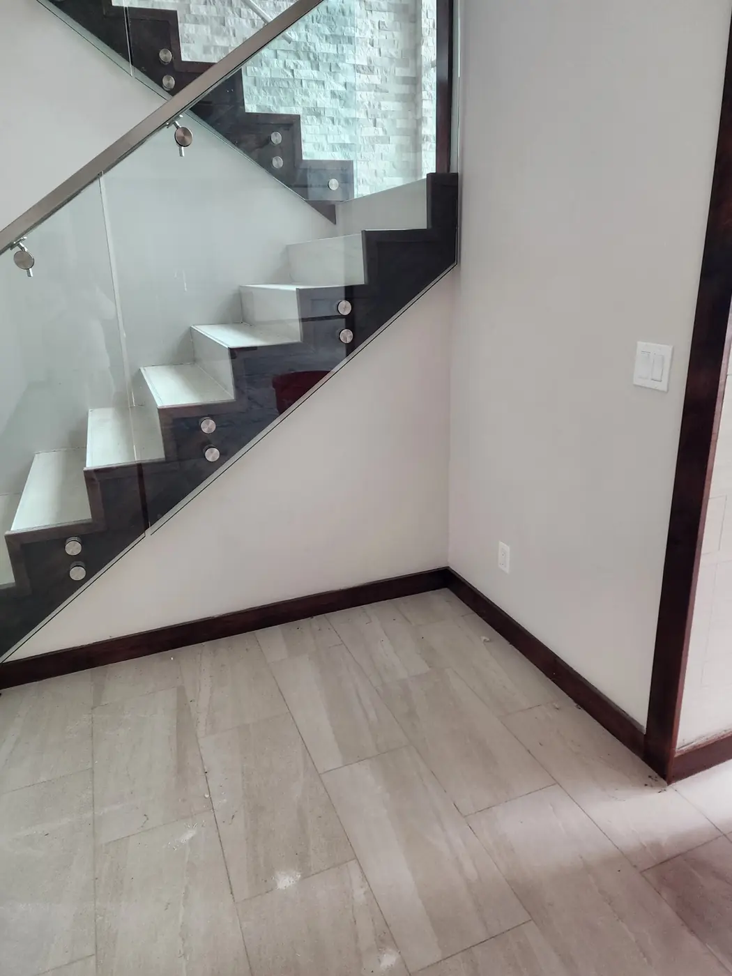 Black Point: floating glass-railed staircase with stained hardwood treads, finished to match the millwork baseboards