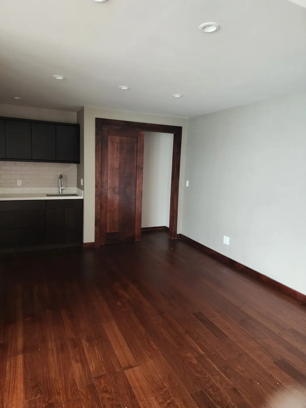 Black Point: kitchen entry with hand-stained pine pocket door, finish reading as a single tone with the matched flooring