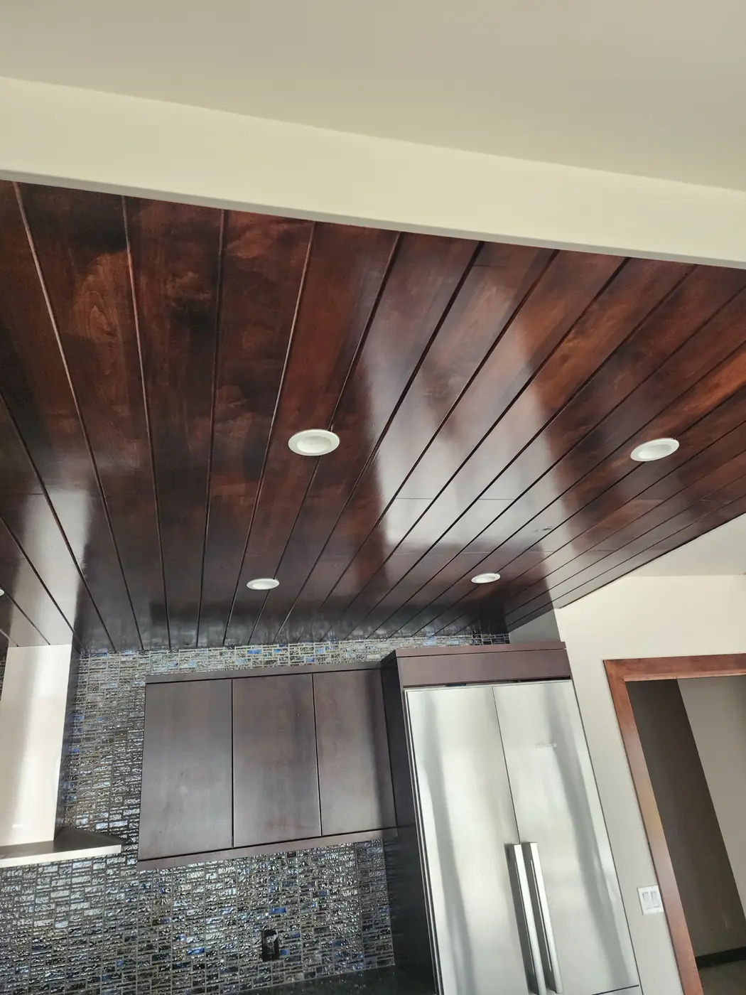 Black Point: stained wood-plank feature wall with recessed downlights, deep walnut finish blended to match cabinetry
