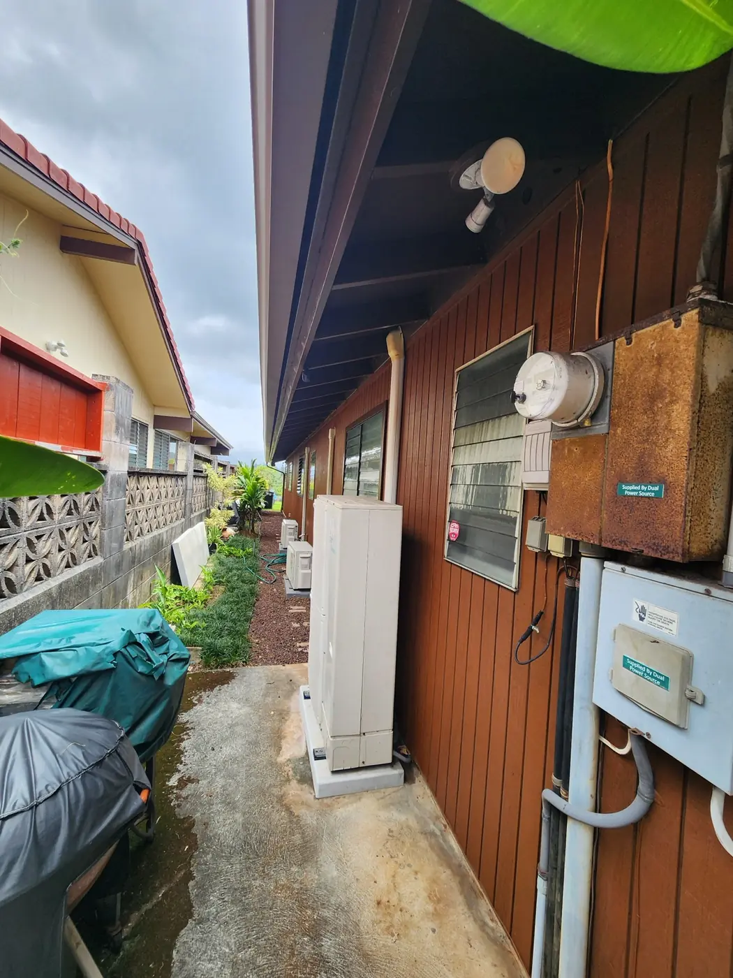 Exterior stain in progress: warm walnut over the siding panels, fixtures masked off