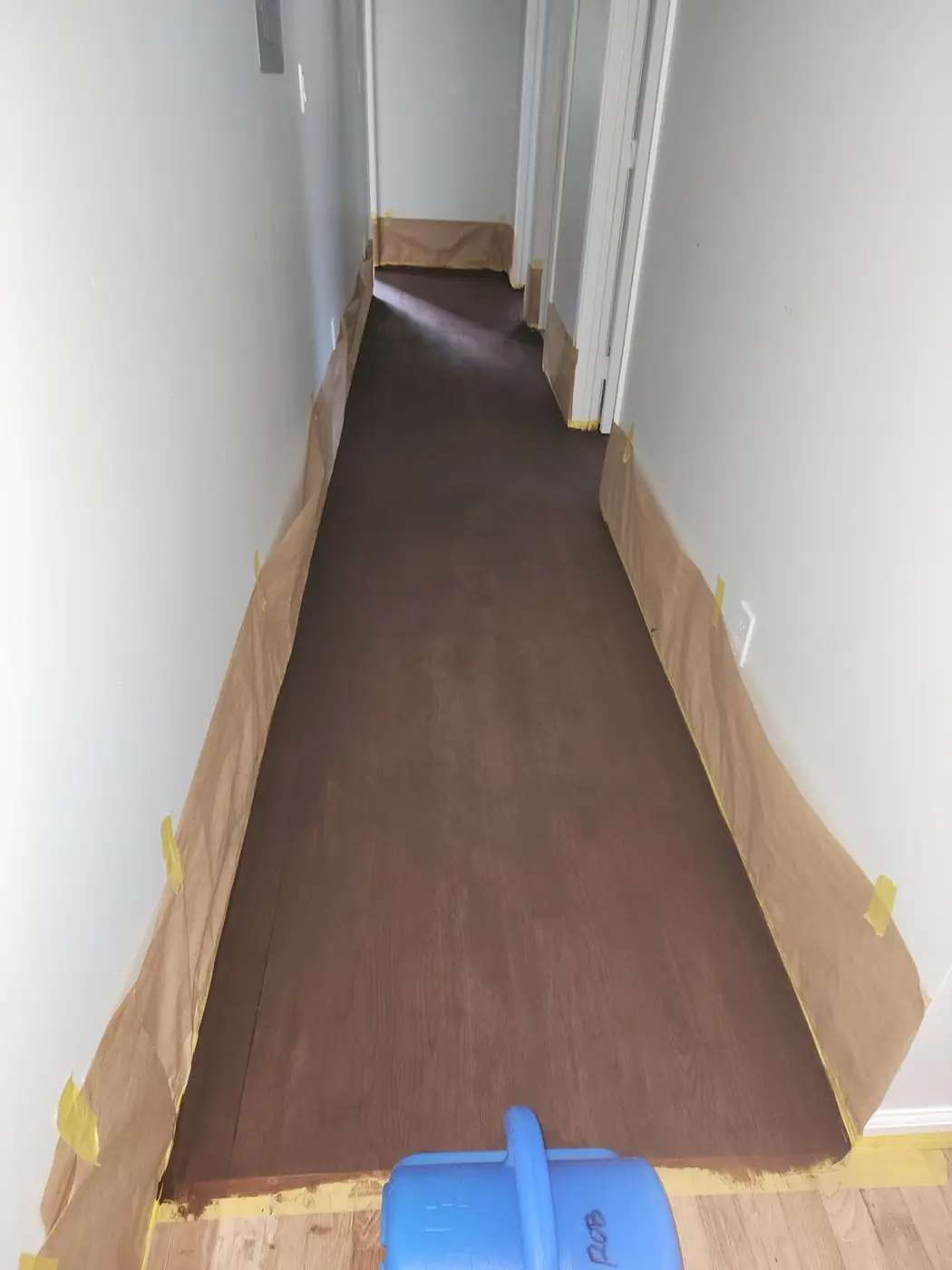 Hardwood floor mid-restoration: stain laid across the planks, drying