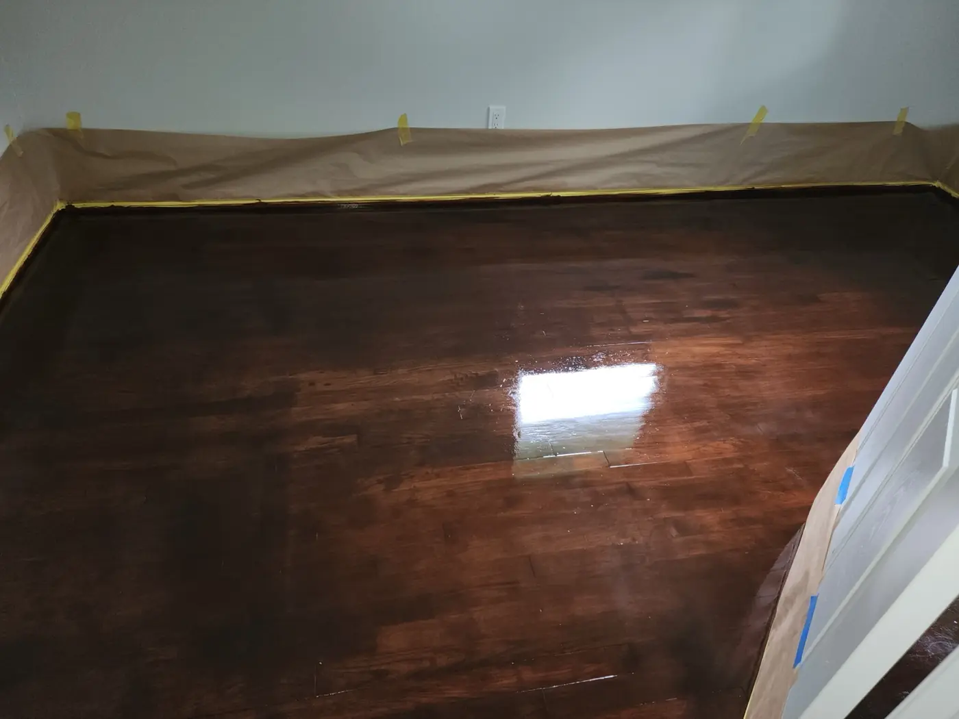 Hardwood floor finish: planks stained warm walnut, paper still in place along the perimeter