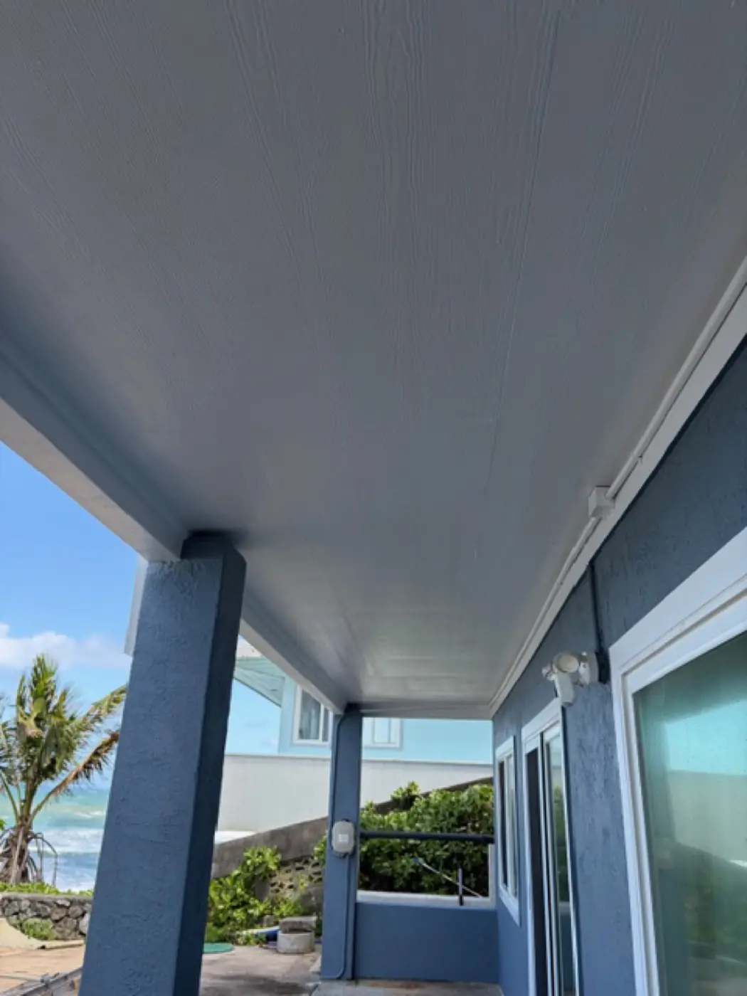 Salt-air spec finish: a side-by-side view of the slate-blue exterior with white lattice detail, ocean view in the gap between buildings