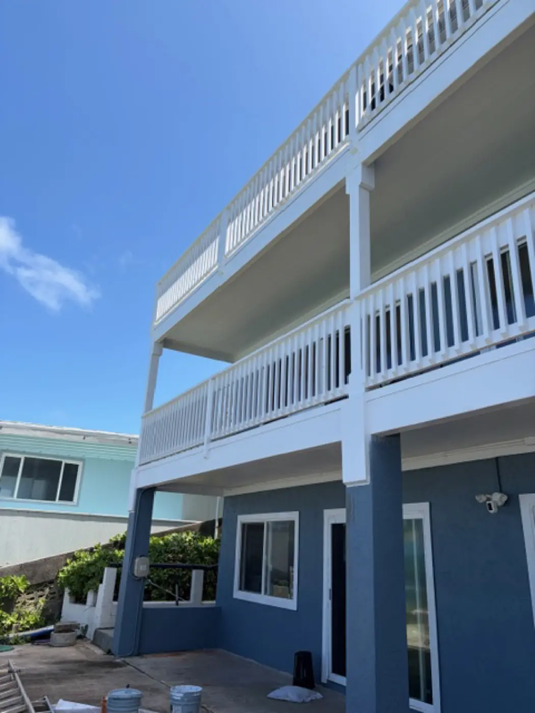 Salt-air spec finish: crisp white louvered soffits over a deep slate-blue exterior, sharp paint lines under bright sky