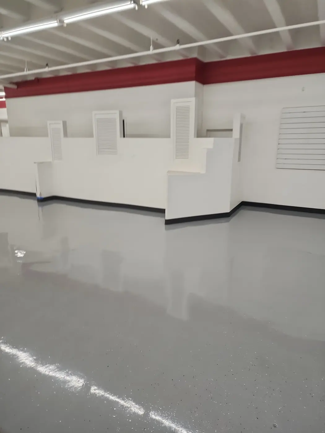 Salvation Army Kailua epoxy floor: finished gray surface under the red-truss ceiling, ready for retail traffic